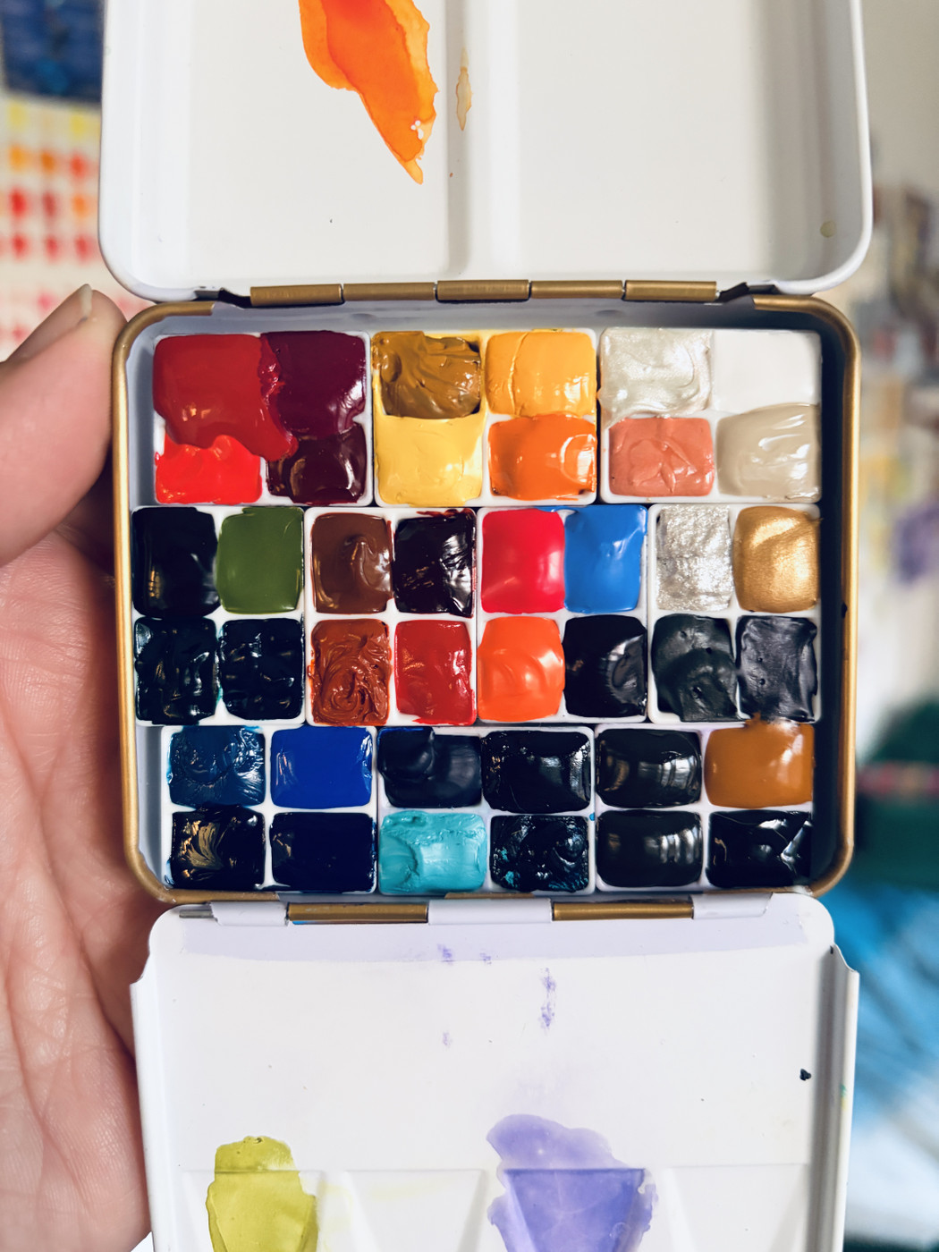 A small metal palette filled with itty bitty paint pans, probably one-quarter size of a regular half pan. Forty colors total, including fun ones like Opera pink (fluorescent!) and Aussie Gold.