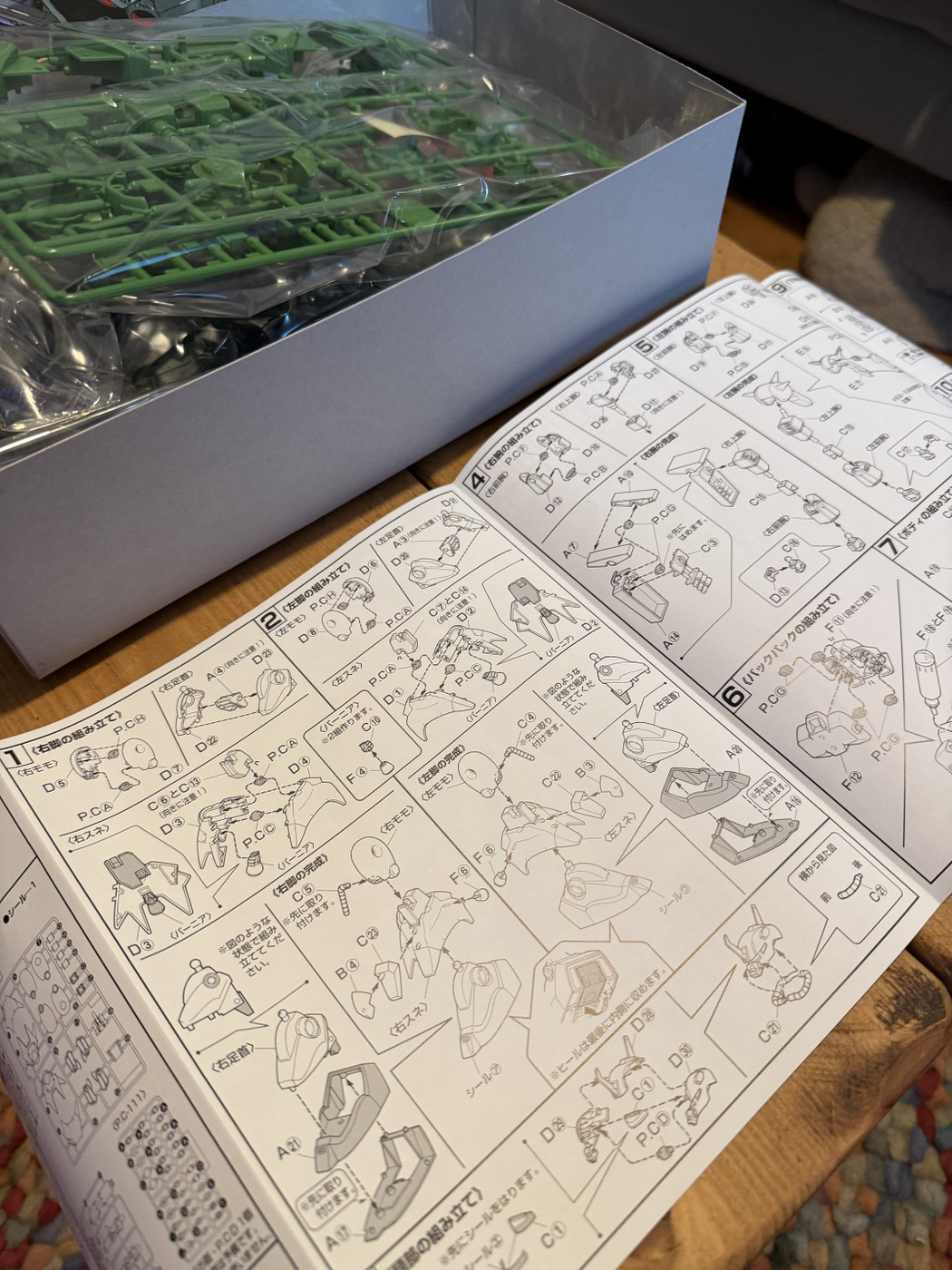 Green plastic model parts and instruction manuals on a wooden surface.