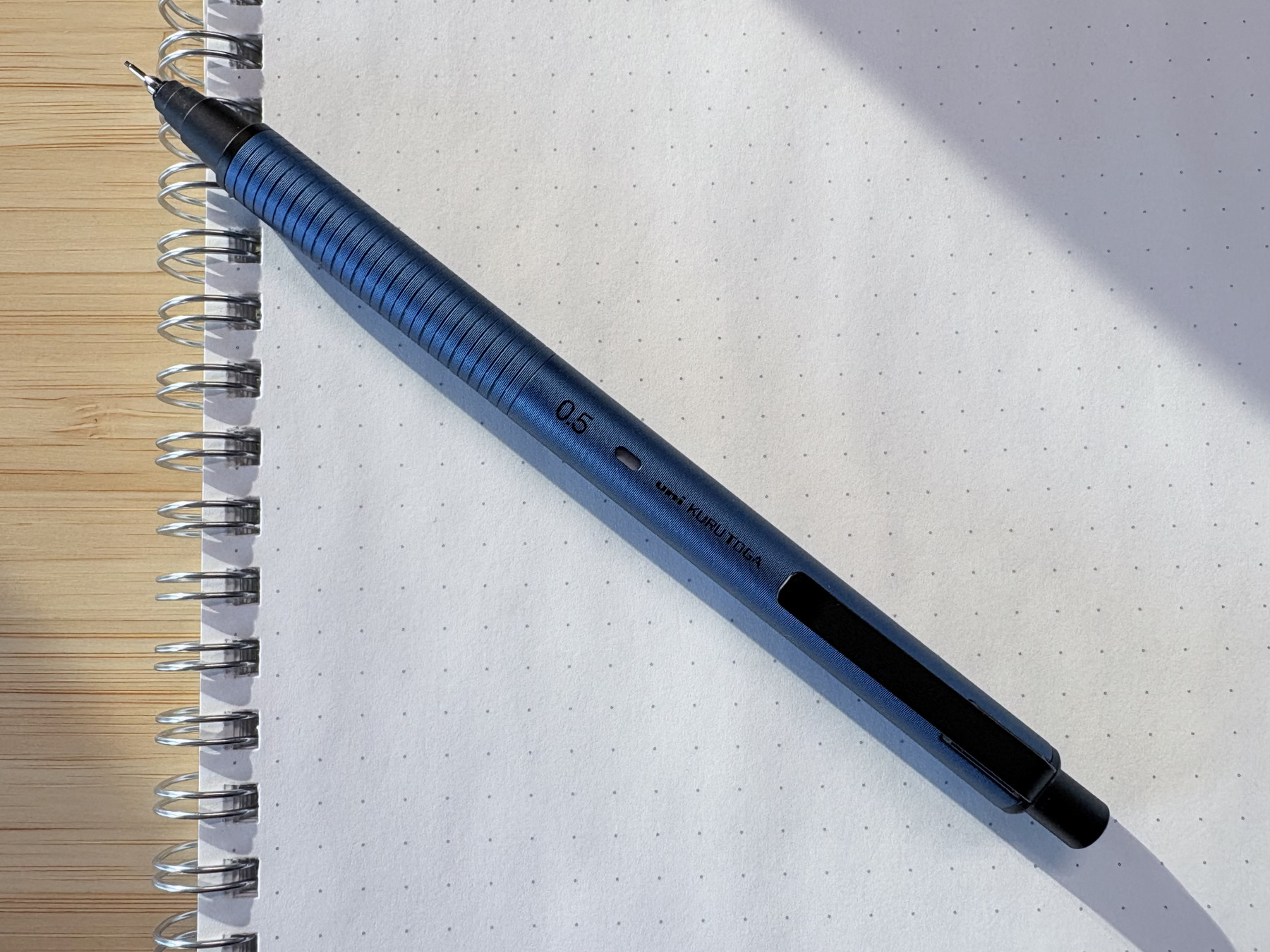 Uni Kuru Toga metal body mechanical pencil on a dot-grid notebook