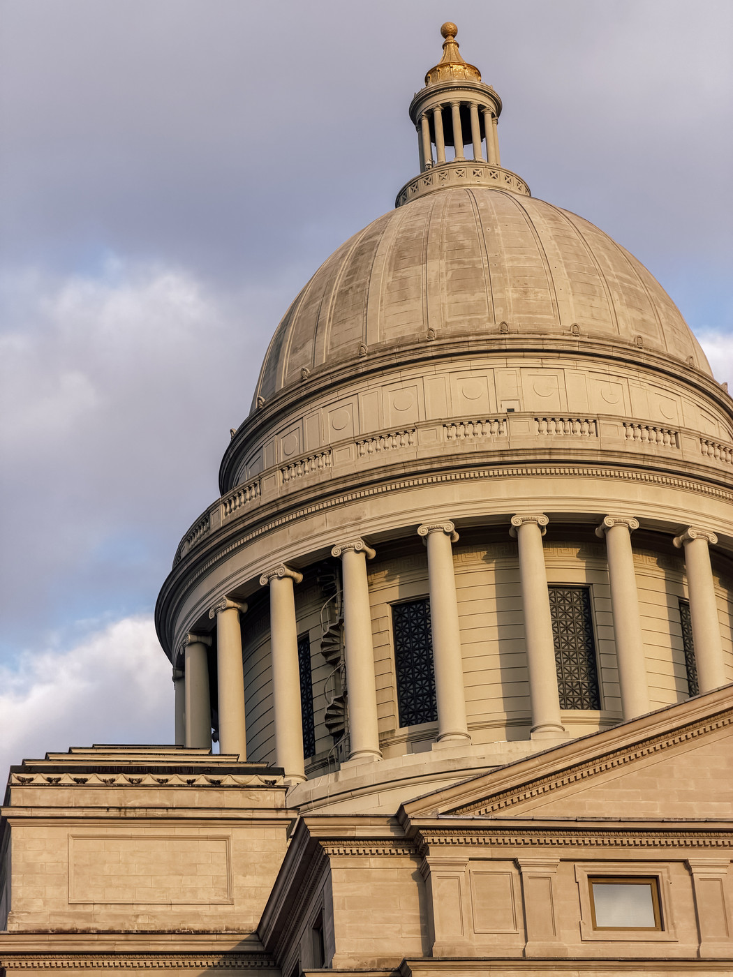 A neoclassical dome with columns is prominently featured under a cloudy sky.