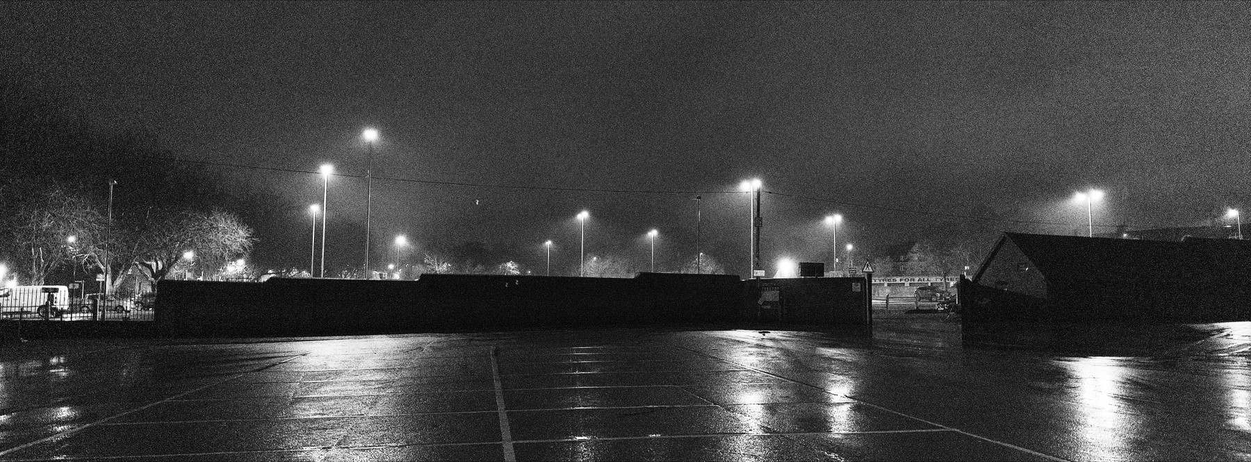 A parking lot under a foggy night sky with streetlights.
