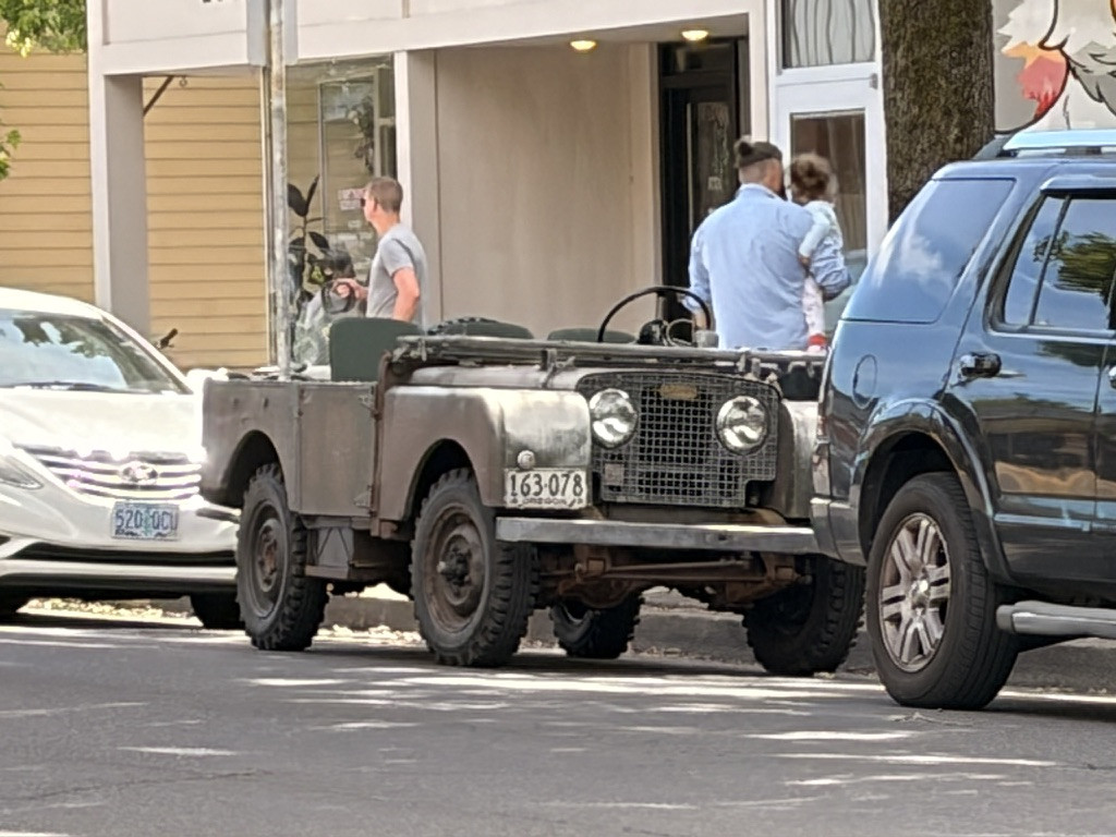 A very old dark green military jeep, probably from the early 50’s.