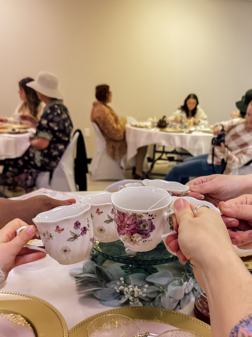 A group of people are toasting with decorative teacups at a tea party.