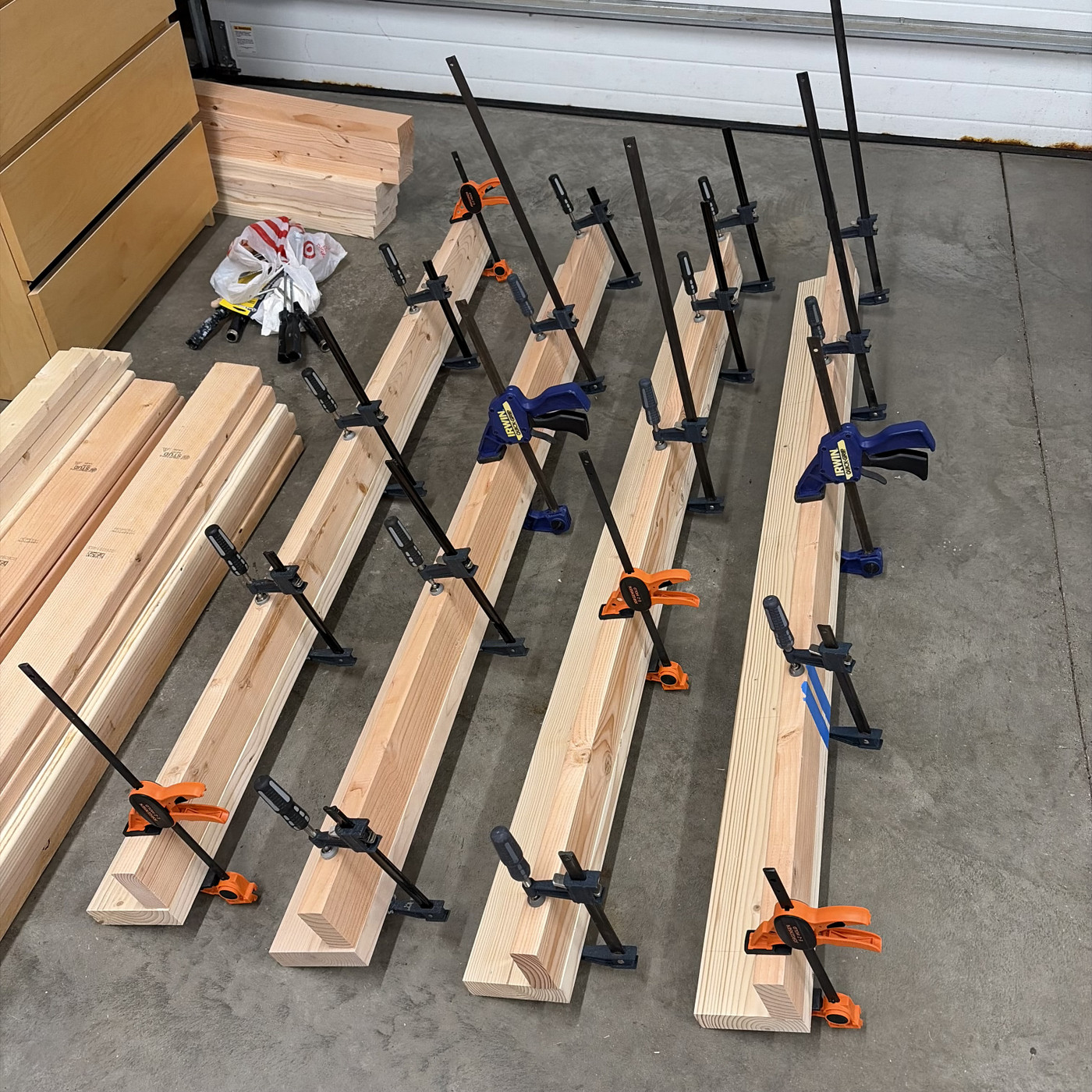 Four loft legs, each in an ‘L’ shape, each clamped with 5 woodworking clamps.