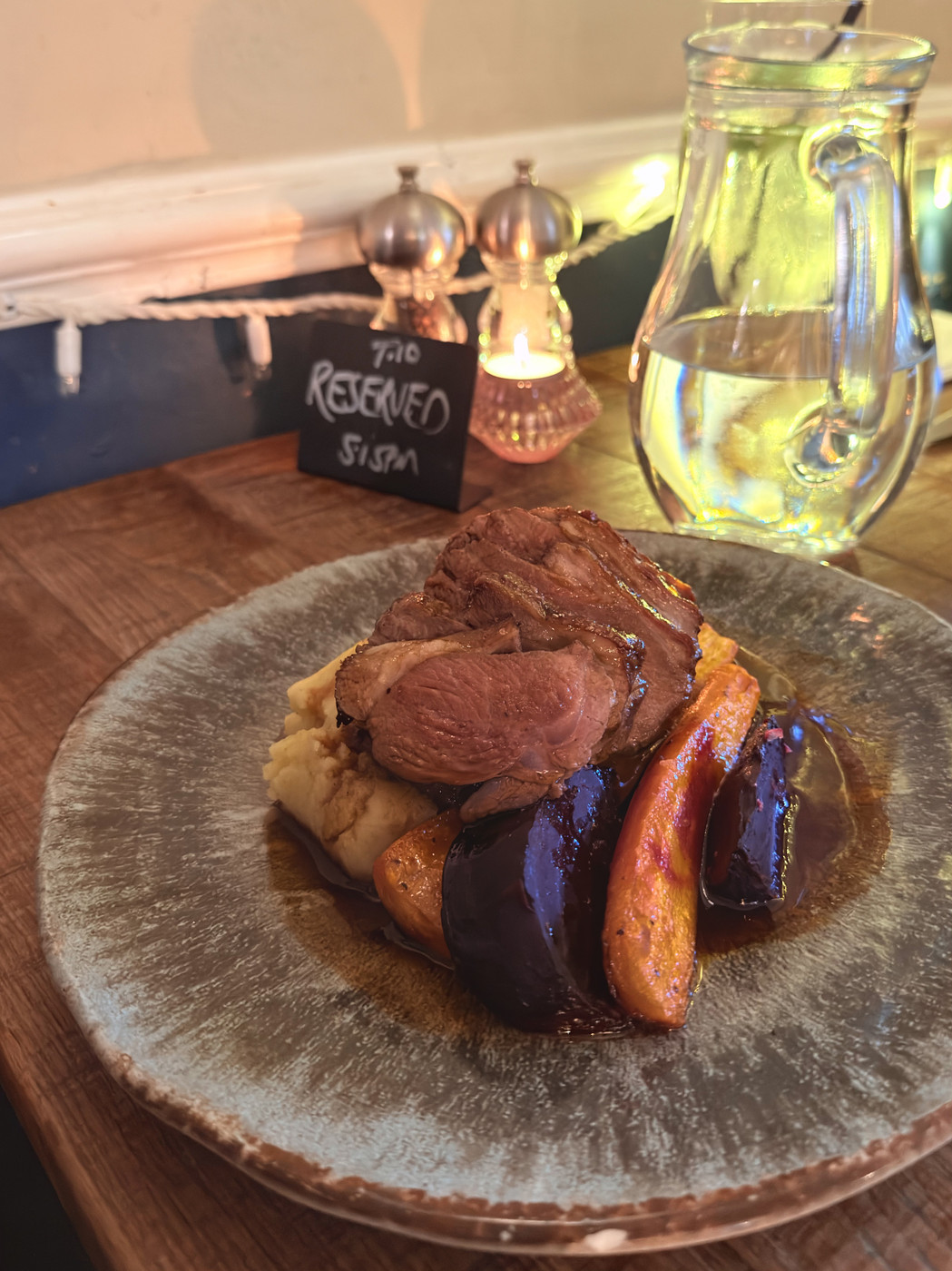 Sliced roast lamb on mashed potato with charred carrots and glazed beetroot wedges, drizzled with rich gravy.