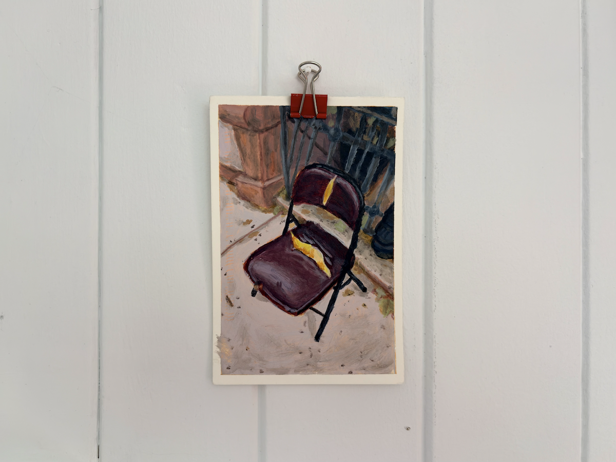 Small painted study clipped to a white panelled wall with a red binder clip, depicting a maroon folding chair marked by bright yellow highlights, set against a loosely rendered indoor background.