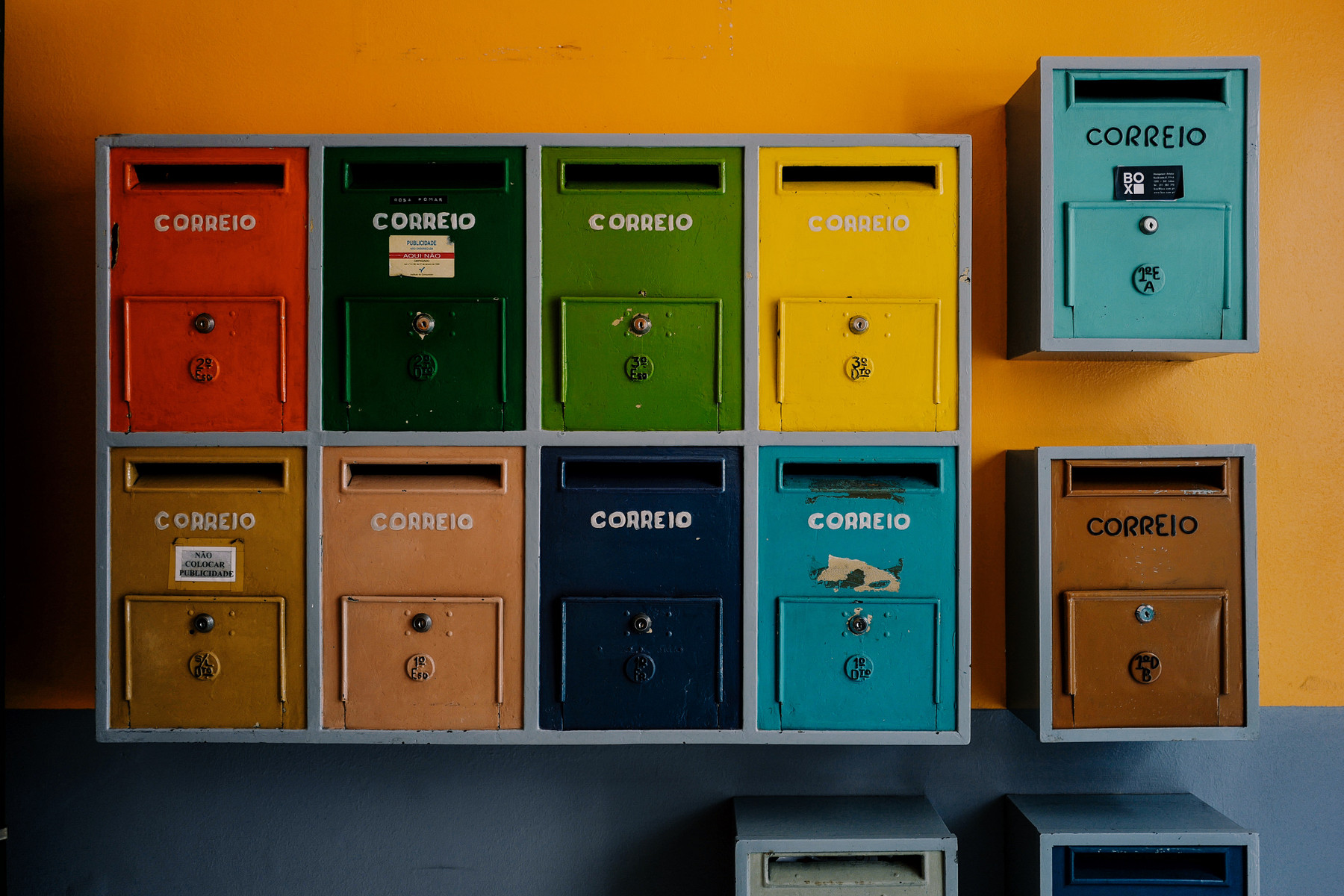 Colorful mailboxes on a yellow wall.