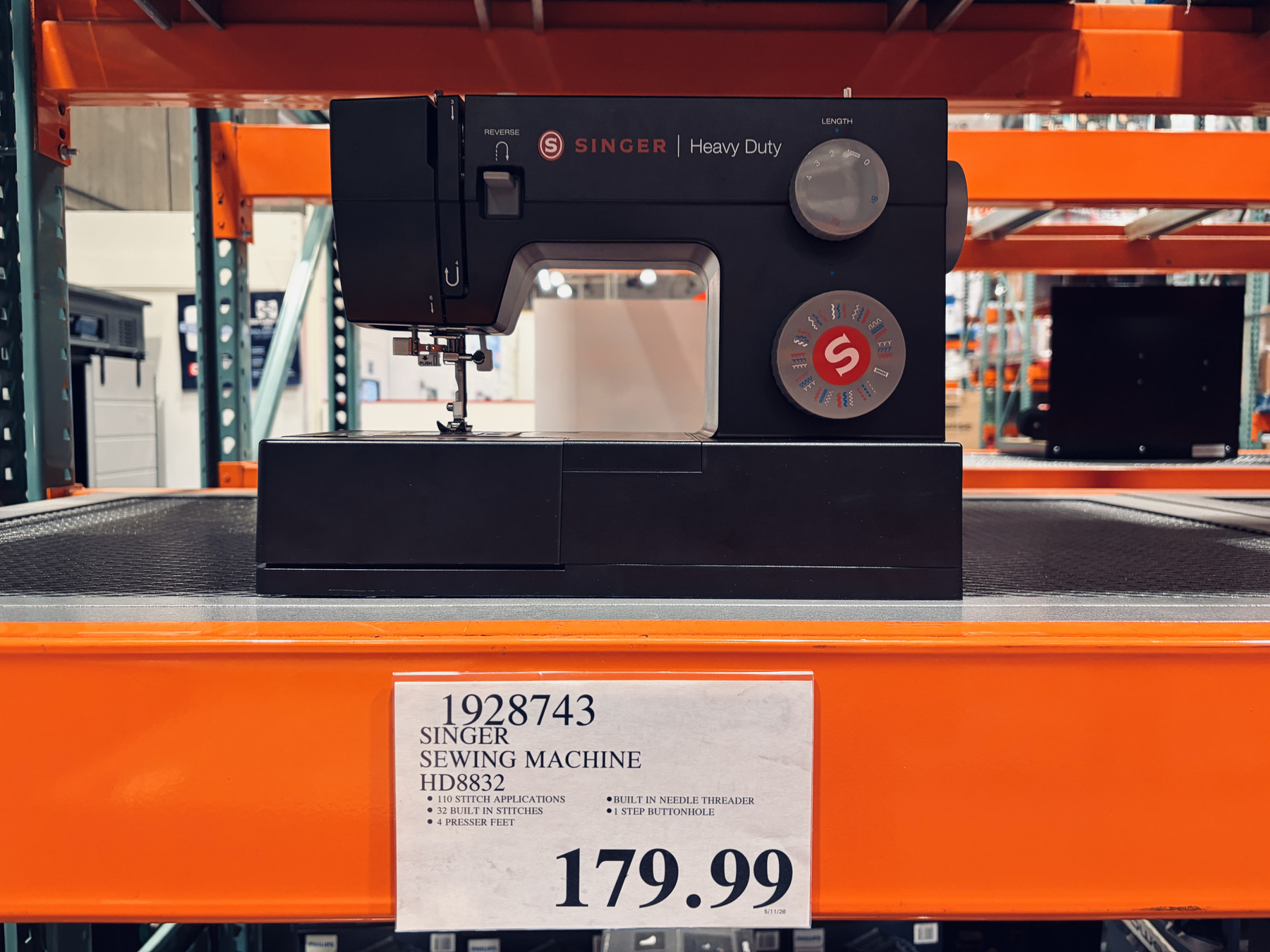 A black Singer sewing machine on display on a Costco shelf, with $179.99 below it.