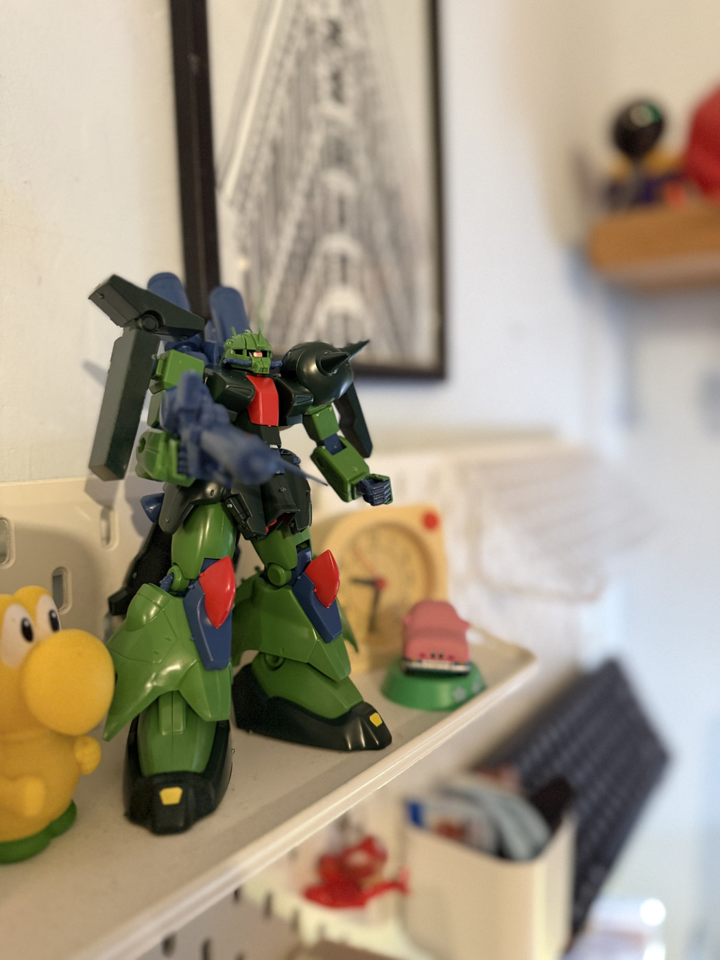 A green and black robot figurine next to a yellow figurine on a white surface.