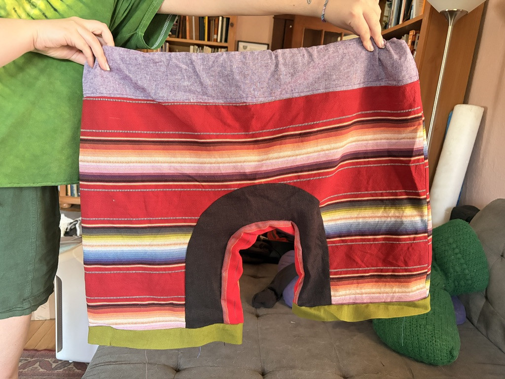 Jupiter holding up the shorts, a striped print in red, with a black panel along the crotch.